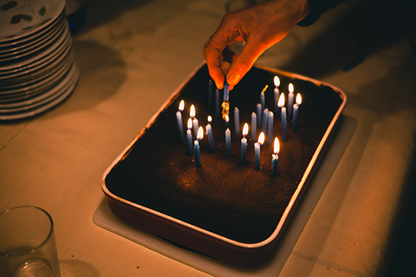 Foto eines Kuchens mit Kerzen und einer Hand, die die Kerzen anzündet