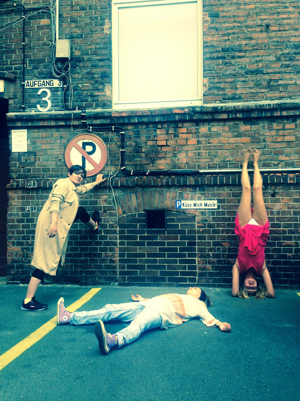 Photography of three people, standing, lying and in handstand in a Berlin backyard