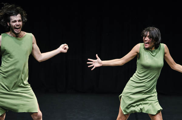 Photo of two dancers in motion in green dresses in stage area