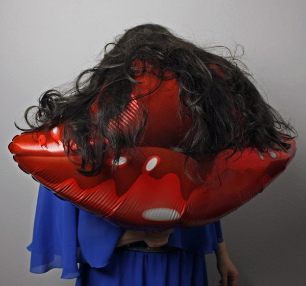 Photo with a mouth shaped balloon of a person with long brown hair wearing, face not visible, blue dress
