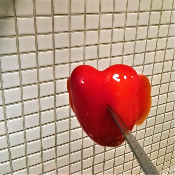 Photo of heart shaped red seemingly liquid object on white tiles